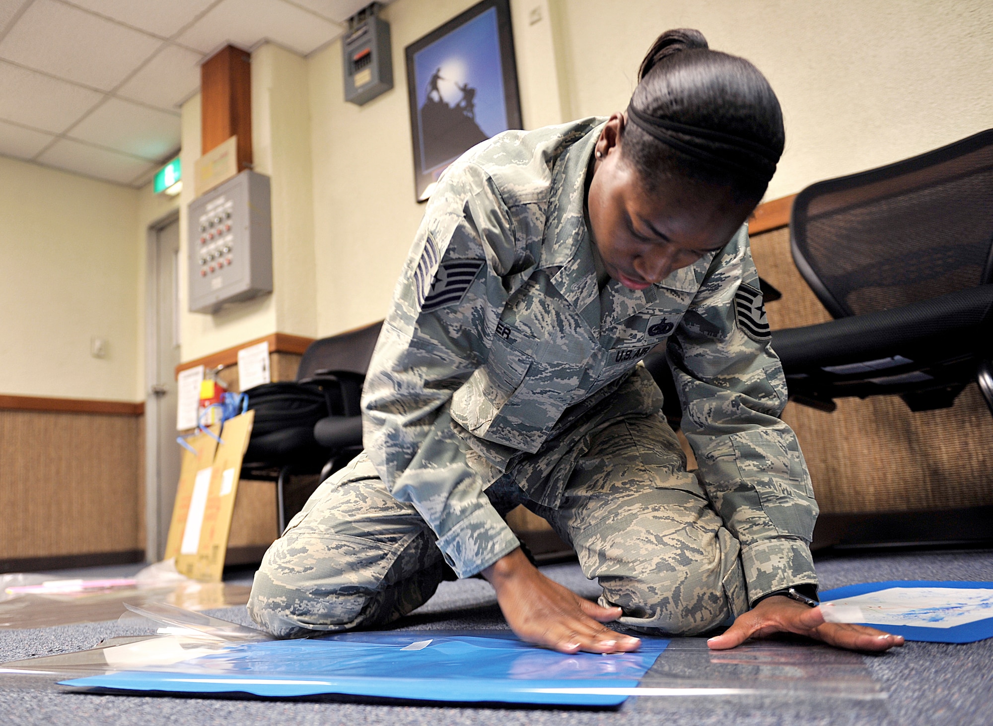 U.S. Air Force Tech. Sgt. Naka Turner, 18th Logistics Readiness Squadron central storage supervisor, wraps artwork drawn by special needs children Oct. 7, 2015, on Kadena Air Base, Japan. Ten Airmen from Kadena volunteered to wrap 273 pieces of art for the Kadena Special Olympics Art Exhibit, which will be held at Main City Shopping Mall San-A in Uruma City from Oct. 15-18 from 9 a.m. to 7 p.m. each day and is open to the public. (U.S. Air Force photo by Naoto Anazawa)