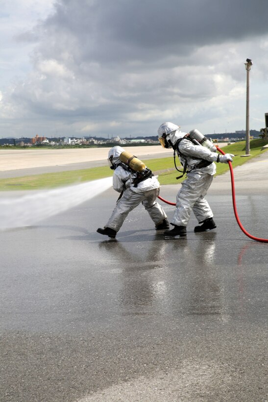 Marines with Aircraft Rescue and Fire Fighting, Headquarters and Headquarters Squadron, practice moving together and communicating. The front Marine is a handline man and controls the flames while the rear Marine, known as the rescue man, points out the location of fires and pulls anyone inside the aircraft to safety. ARFF Marines are one of the safety measures MCAS Futenma uses in case of emergencies. H&HS, MCAS Futenma, Marine Corps Installations Pacific-Marine Corps Base Camp Butler, Japan, reached 100,000 flight hours without incident Oct. 1.
