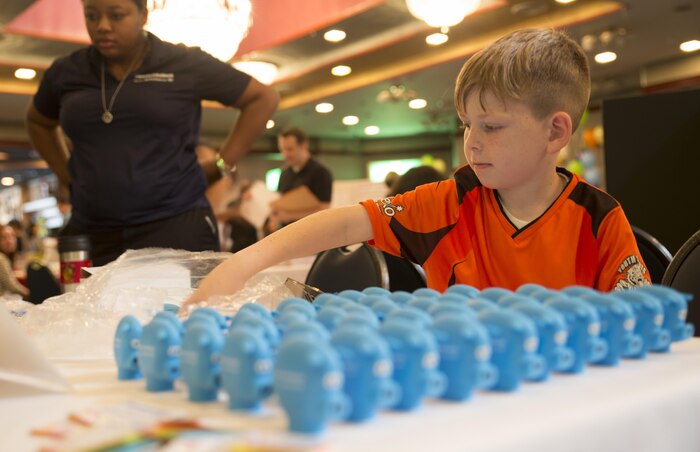 Lucas Henson, Info Expo participant, helps set up a display at the Community Bank table during the Info Expo inside the Club Iwakuni Grand Ballroom aboard Marine Corps Air Station Iwakuni, Japan, Sept. 12, 2015. The Info Expo continues to grow each year, with more and more local Japanese vendors joining, making it easier for station residents to access local travel and services information as well as providing an opening for the Japanese community to experience the American culture.