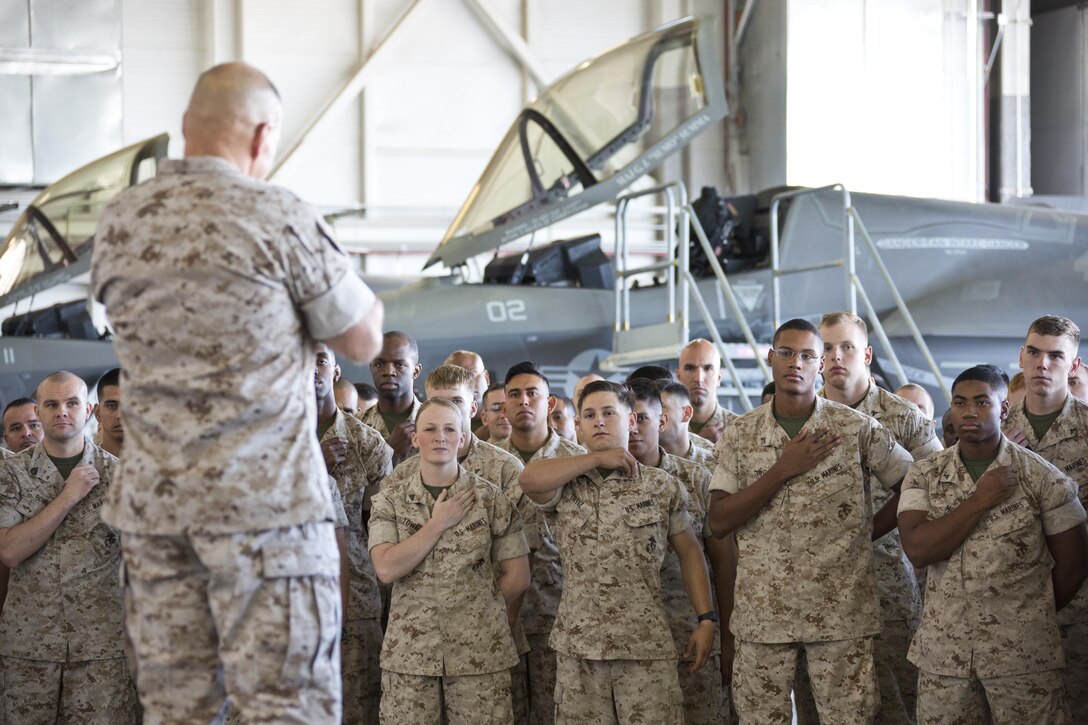 U.S. Marines touch their rank insignia while they listen to Commandant of the Marine Corps, Gen. Robert B. Nelle, at Marine Corps Air Station Yuma, Ariz., Oct. 7, 2015. Neller outlined the Corps current priorities, expectations, listened and answered Marines' questions. (U.S. Marine Corps photo by Sgt. Gabriela Garcia/Released)