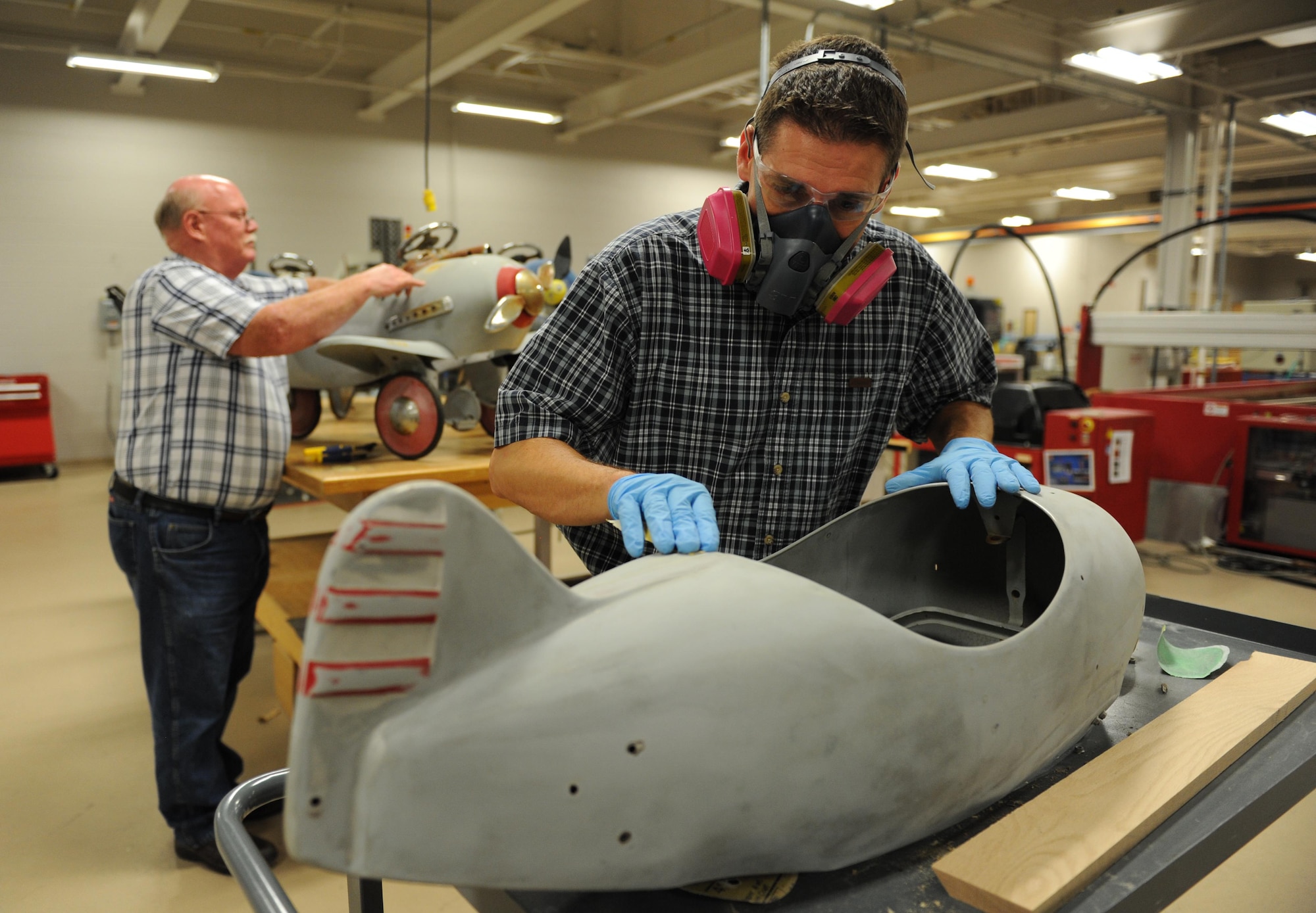 Tomme Lassabe, 81st Training Support Squadron training technology flight chief, and Tom Capers, 81st TRSS machinist and welder, refurbish pedal airplanes at the Trainer Development Center, Oct. 8, 2015, Keesler Air Force Base, Miss. The four pedal airplanes, belonging to the child development center, have been in storage for more than 10 years. (U.S. Air Force photo by Kemberly Groue)