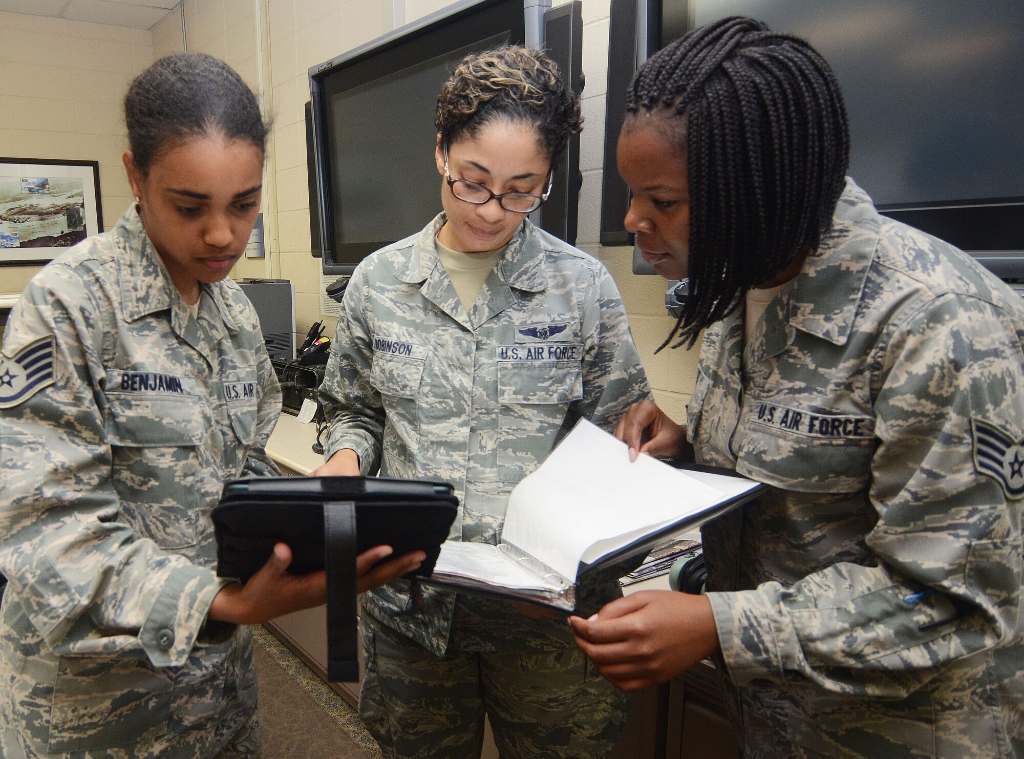 Staff Sgt. Chantel Benjamin, Tech. Sgt. Susan Robinson, and Staff Sgt. Stephanie Lee from the 700th Airlift Squadron, get hands-on experience on the Mobile Mission Kit during its test phase on Dobbins Air Reserve Base, Ga. Sept. 30, 2015. The device is designed to capture a wide variety of accurate and timely mission data using a paperless and real-time process, reducing crew workload, saving costs and improving overall efficiency before, during and after flying missions. (U.S. Air Force photo/Don Peek)