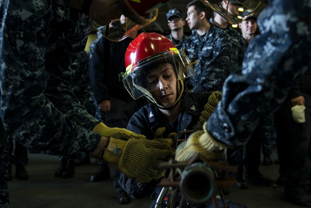 U.S. Navy Petty Officer 3rd Class Berney Jarosz practices pipe-patching during a general quarters drill in the hangar bay of the USS Ronald Reagan in Yokosuka, Japan, Oct. 8, 2015. Jarosz is a machinist's mate. U.S. Navy photo by Petty Officer 3rd Class Nathan Burke