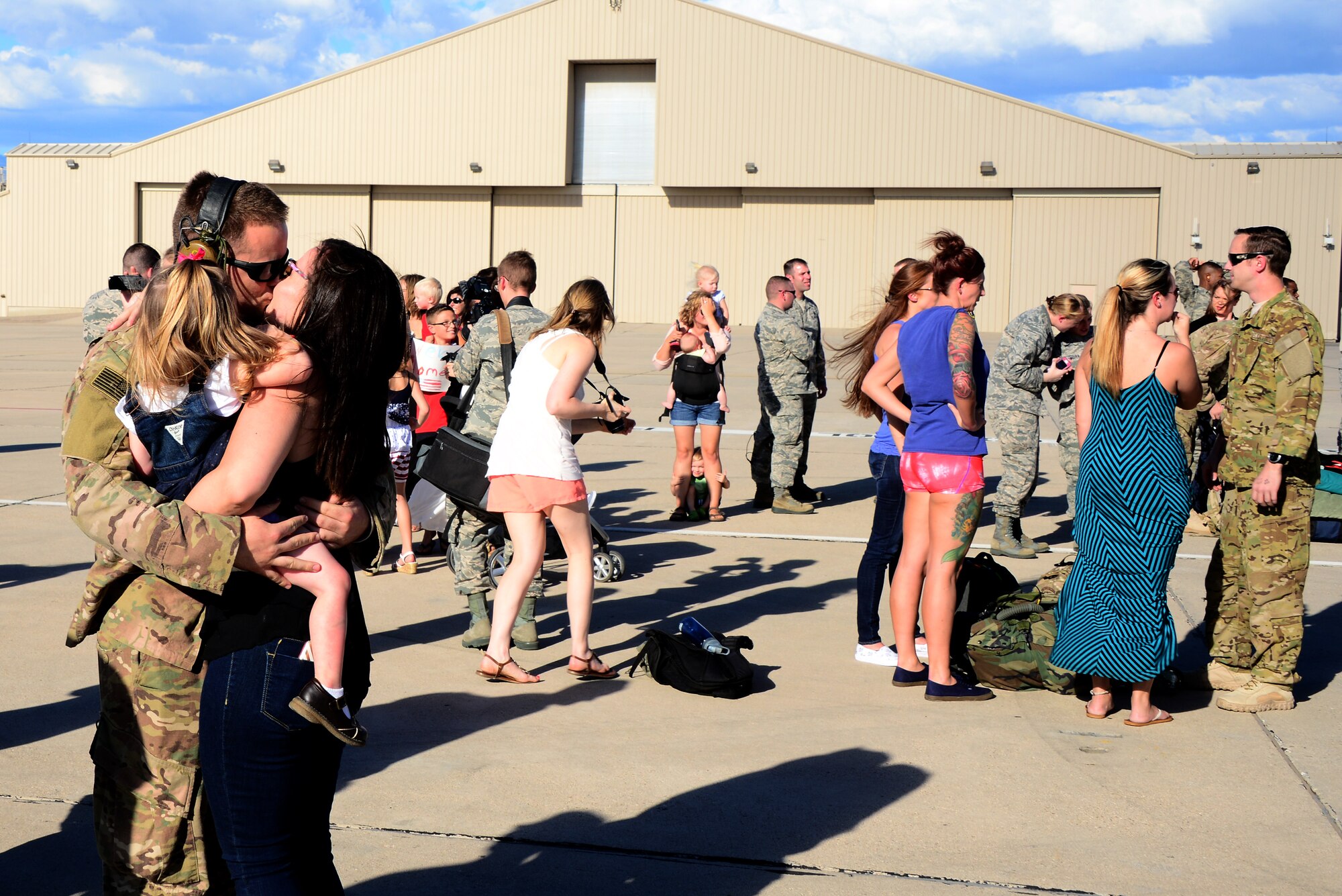 U.S. Air Force Staff Sgt. Zachary Resare 923rd Aircraft Maintenance Squadron, kisses his wife and holds his daughter on the flightline at Davis-Monthan Air Force Base, Ariz., Oct. 9, 2015. Two HC-130J Combat King IIs and 25 Airmen returned from a 4-month deployment to Southwest Asia. (U.S. Air Force photo by Airman 1st Class Mya M. Crosby/Released) 