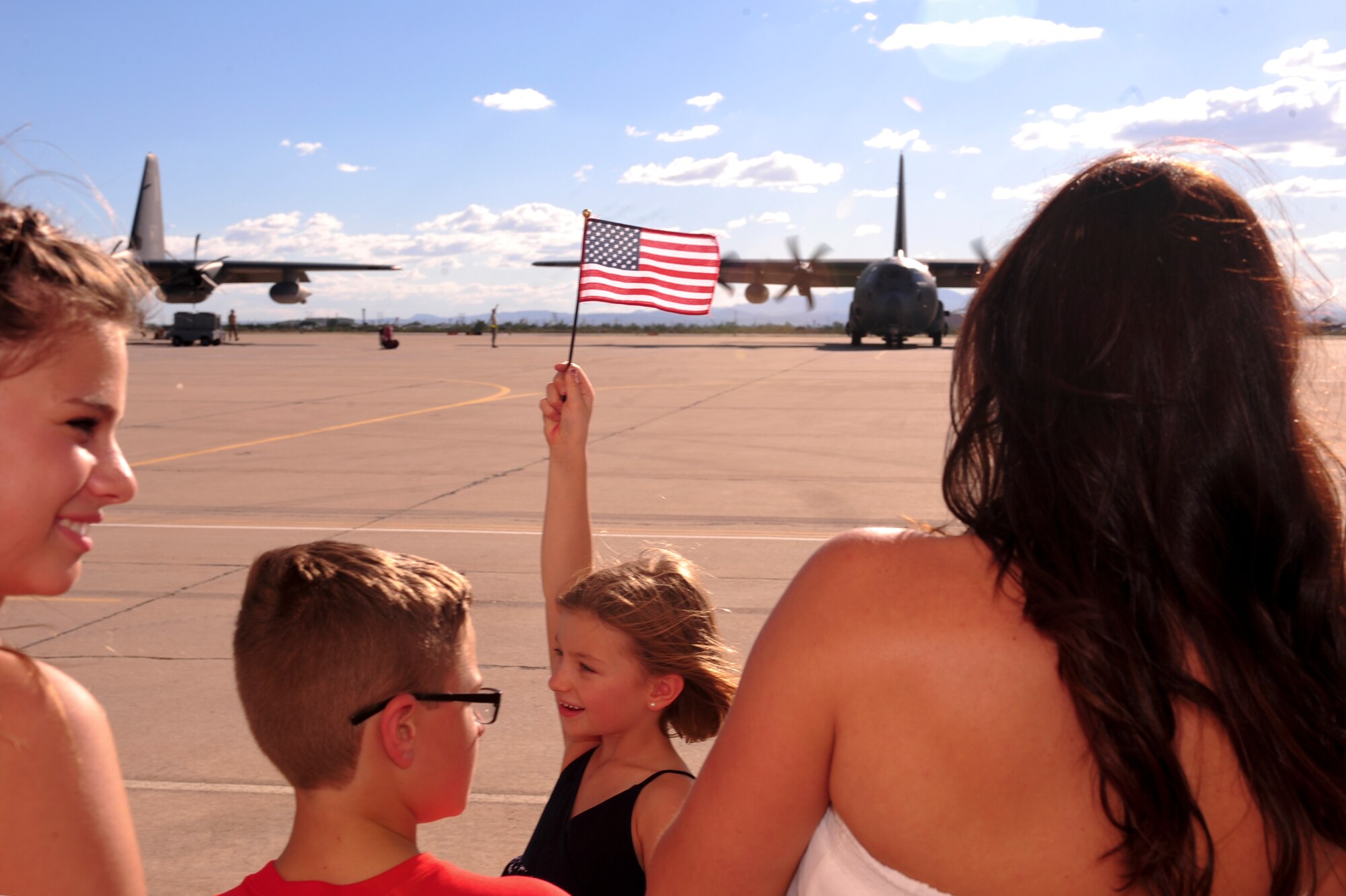 Friends and family wait to greet U.S. Airmen from the 563rd Rescue Group while Two HC-130J Combat King IIs park on the flightline at Davis-Monthan Air Force Base, Ariz., Oct. 9, 2015. Approximately 25 Airmen returned home from a 4-month deployment to Southwest Asia. (U.S. Air Force photo by Airman Basic Nathan H. Barbour/Released)