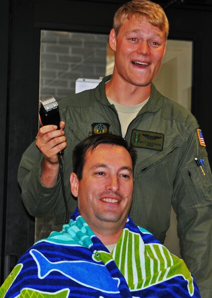 1st Lt. Matthew Anderson, 6th Special Operations Squadron pilot, prepares to shave the head of his boss, Lt. Col. Casey Ward, 6th SOS commander, at Duke Field, Fla., Oct. 8, 2015. Ward and two others with ties to the squadron put their hair on the line as part of a teambuilding event for the special operations unit. (U.S. Air Force photo/Lt. Col. James R. Wilson)