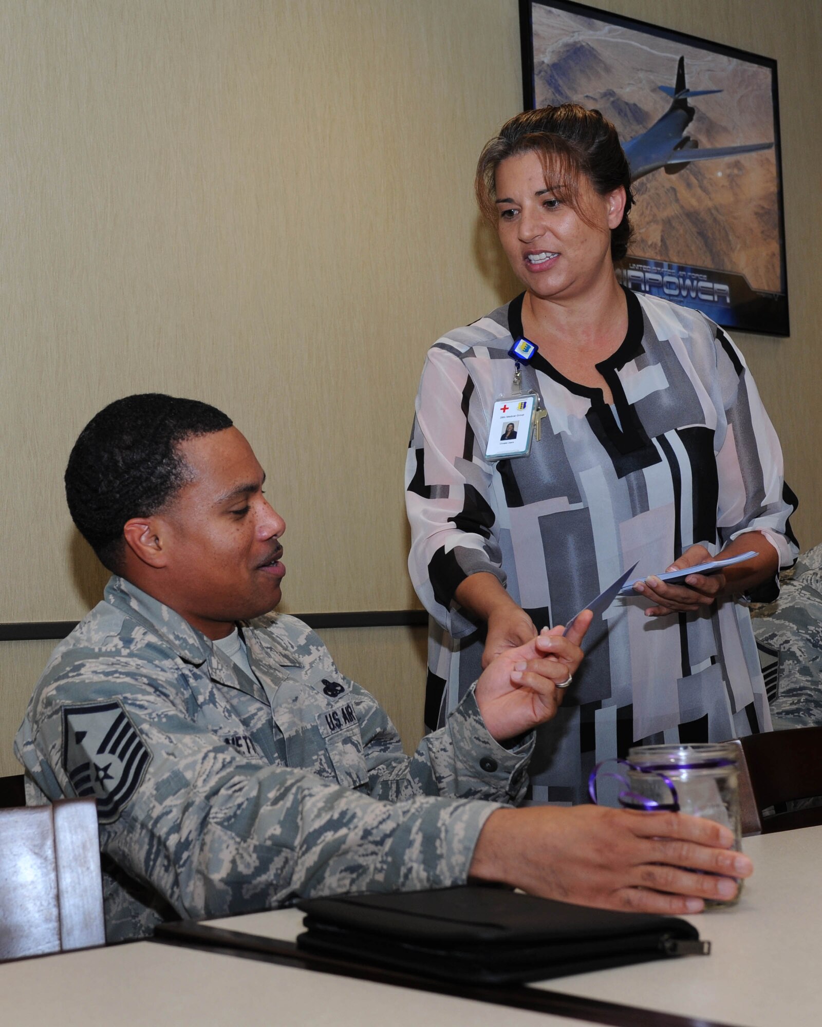 Master Sgt. Edward Nettles, 28th Operations Support Squadron first sergeant, left, receives an invitation to the Purple Ribbon Luncheon and a candle from Christle Usera, 28th Medical Group Family Advocacy intervention specialist, right, at Ellsworth Air Force Base, S.D., Oct. 1, 2015. The 2015 Domestic Violence Awareness Month campaign is “Light in the Window,” which signifies community solidarity toward ending domestic violence and provides an opportunity to discuss the conditions under which domestic violence may occur. (U.S. Air Force photo by Senior Airman Hailey R. Staker/Released) 
