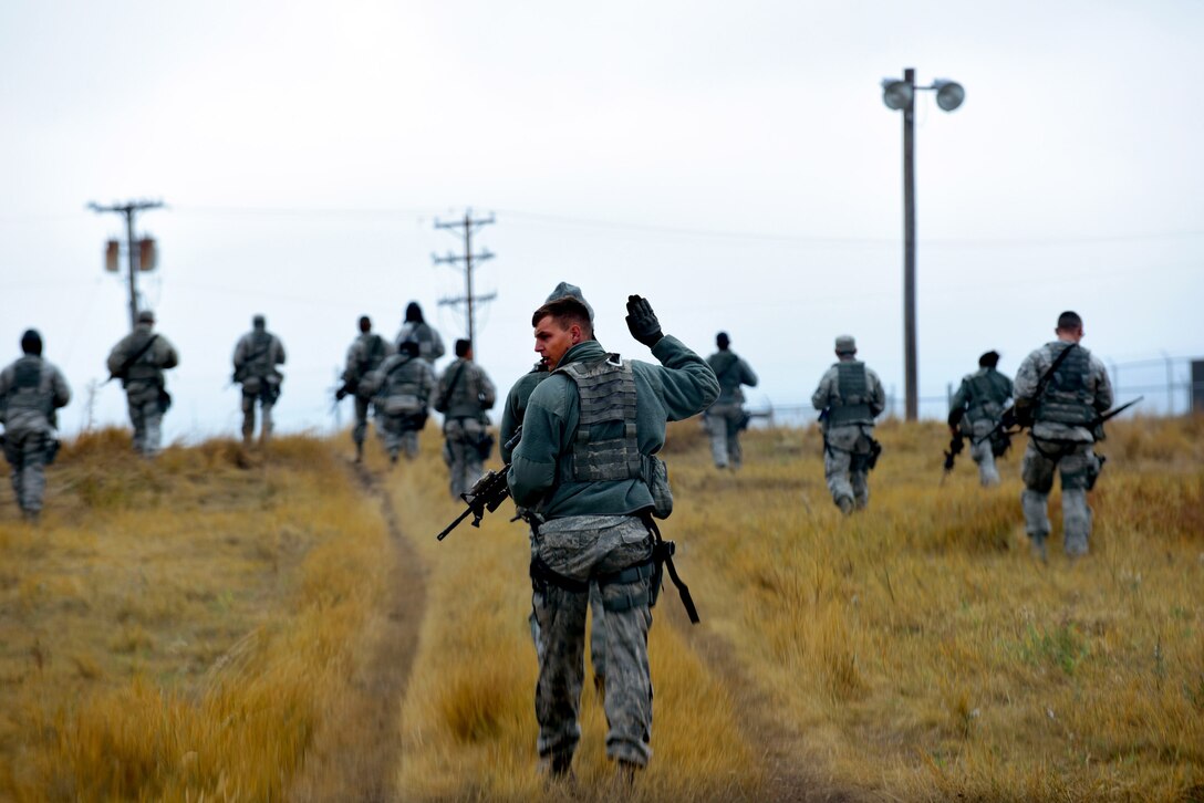 Staff Sgt. Matthew Eichner, 28th Security Forces Squadron response force leader, signals his squad members to move forward during a Shoot, Move, Communicate training at Ellsworth Air Force Base, S.D., Sept. 29, 2015. Security Forces members participated in a simulated sweep of a hostile area where they engaged and neutralized enemy forces. (U.S. Air Force photo by Airman 1st Class James L. Miller/Released)