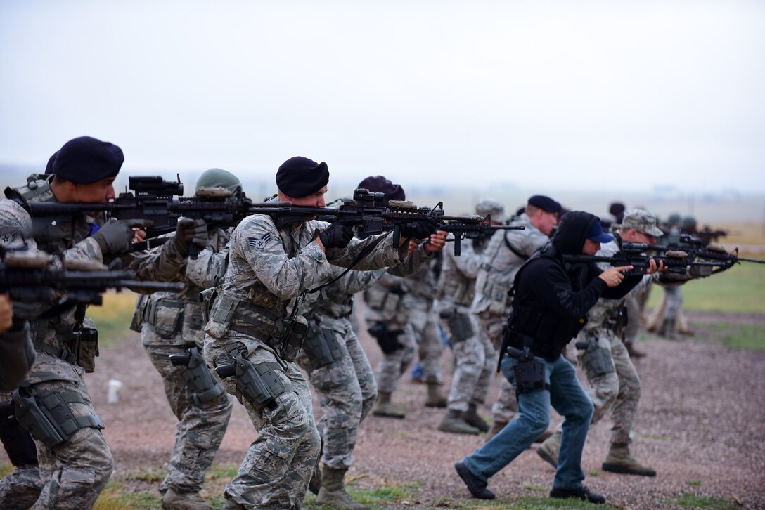 Members of the 28th Security Forces Squadron move at the low ready position during a Shoot, Move, Communicate training event at Ellsworth Air Force Base, S.D., Sept. 29, 2015. Airmen and civilian security forces members practiced engaging their targets, communicating and protecting one another on a simulated battlefield. (U.S. Air Force photo by Airman 1st Class James L. Miller/Released)