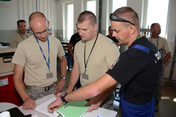 U.S. Air Force Senior Master Sgt. Peter Seibel, left, armament section supervisor, joins U.S. Air Force Tech. Sgt. Steven Heggie, center, aircraft armament specialist for the Wisconsin Air National Guard's 115th Fighter Wing to review technical order data with their Polish air force counterparts from the 10th Fighter Squadron at Łask Air Base Sept. 1, 2015, while deployed in support of U.S. Aviation Detachment Rotation 15-4. The annual training exercise hosted by the Av-Det is designed to enhance bilateral defense ties between Poland and the United States, while strengthening the interoperability of NATO Allies. (U.S. Air National Guard Photo by Master Sgt. Paul Gorman/Released)