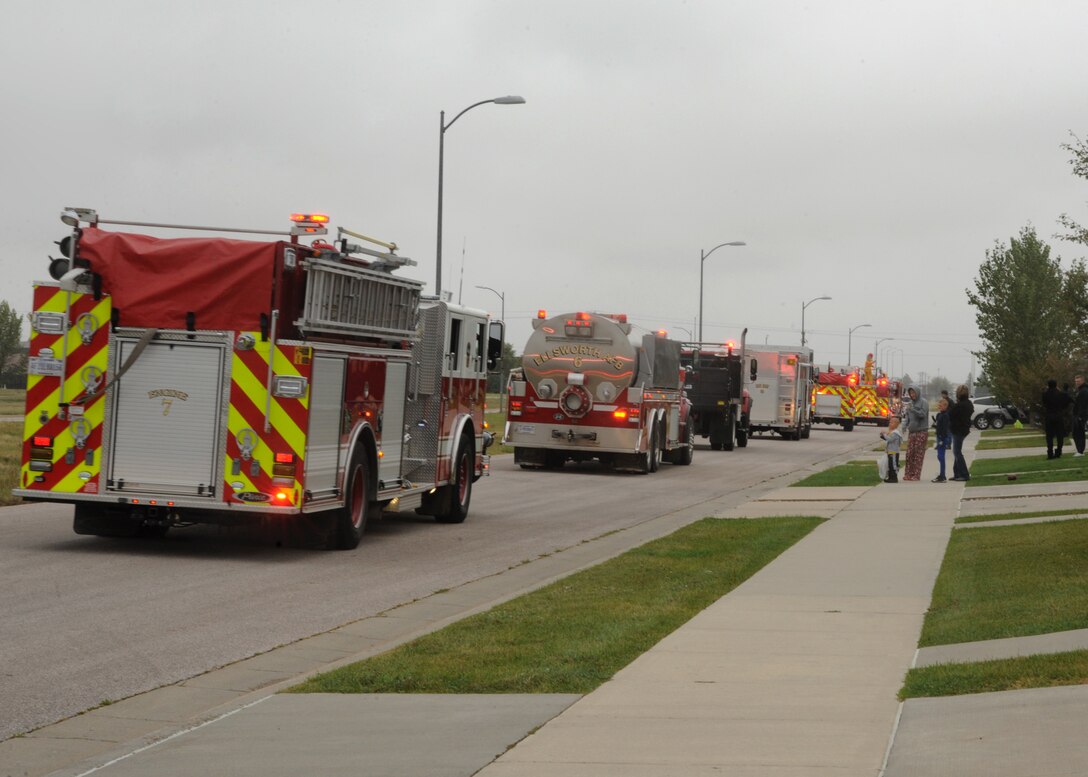 Families watch as the Ellsworth fire department drive thru base housing during the Fire Prevention Week parade and open house at Ellsworth  Air Force Base, S.D., Oct. 3, 2015. The theme for this year's Fire Prevention Week is "Hear The Beep Where You Sleep," encouraging residents to be vigilant and ensure the proper function of smoke alarms in their homes. (U.S. Air Force photo by Airman 1st Class Denise M. Nevins/Released)