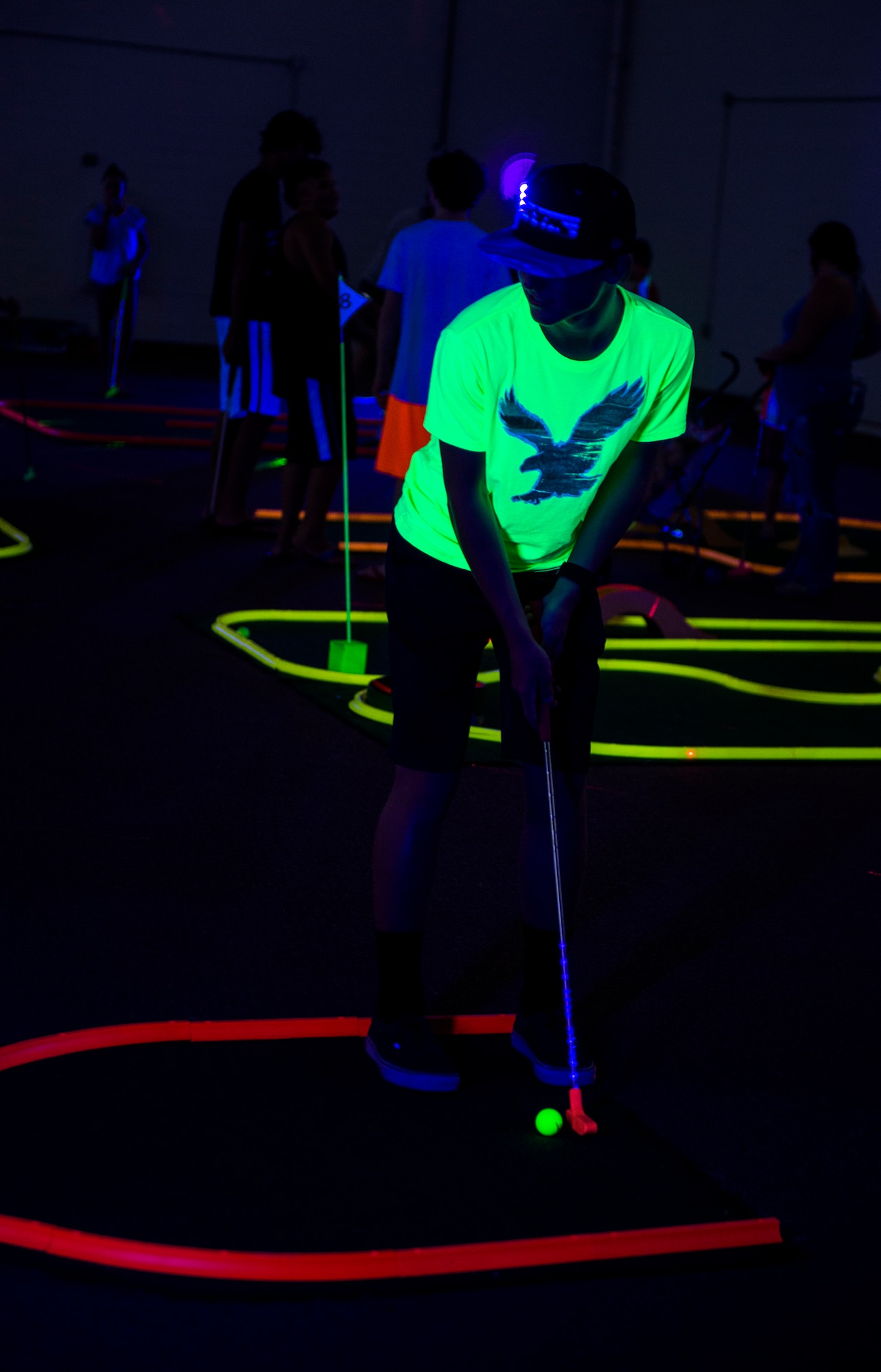 Carson, son of U.S. Air Force Col. Joseph Locke, 93d Air Ground Operations Wing commander, swings a club during Recharge for Resiliency Glow in the Dark miniature golf, July 24, 2015, at Moody Air Force Base, Ga. Recharge for Resiliency was designed to assist families, couples and single Airmen in reintegrating and recharging before and after a deployment. (U.S. Air Force photo by Senior Airman Ceaira Tinsley/Released)