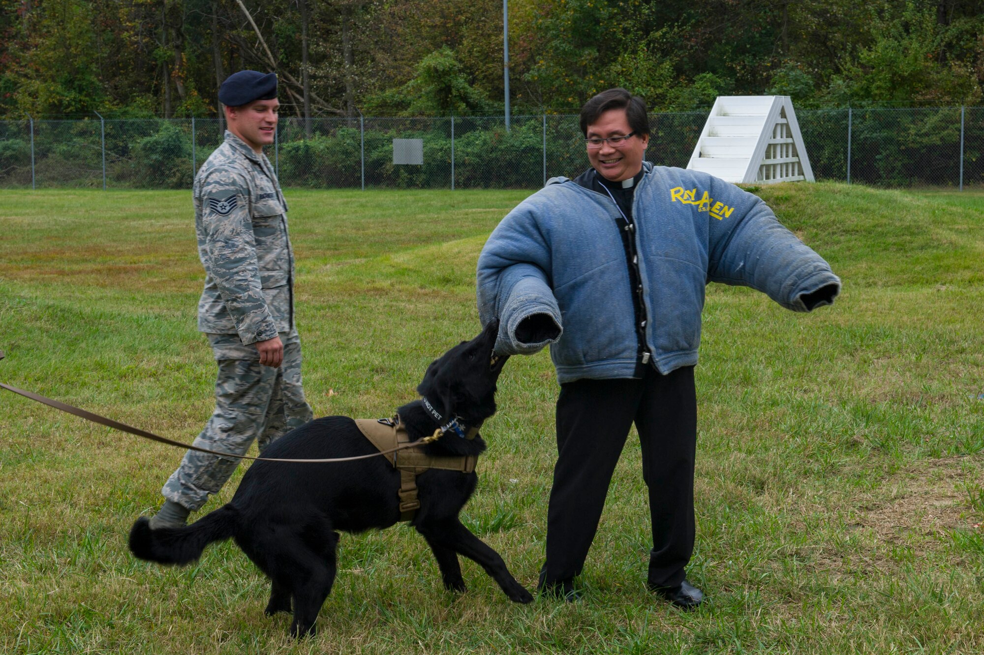 Father Duong Nguyen, Catholic Priest of the Diocese of Venice, Florida, feels what it is like to be attacked by a military working dog Oct. 7, 2015 at Joint Base Andrews, Md. Nguyen and nine other priests from all over the U.S. visited JBA as part of a familiarization visit to each branch of the military put on by the Archdiocese for the Military Services. (Air Force photo by Senior Airman Dylan Nuckolls/Released)