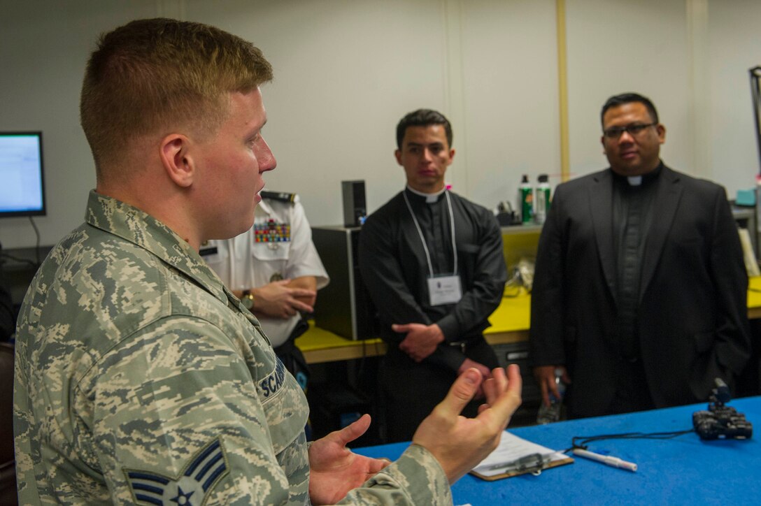 Senior Airman Mitchell Scarbrough, 811th Operation Support Squadron air crew flight equipment technician, talks to Priests about some of the gear pilots wear while they fly Oct. 7, 2015 at Joint Base Andrews, Md. Ten priests from all over the U.S. visited JBA as part of a familiarization visit to each branch of the military put on by the Archdiocese for the Military Services. (Air Force photo by Senior Airman Dylan Nuckolls/Released)