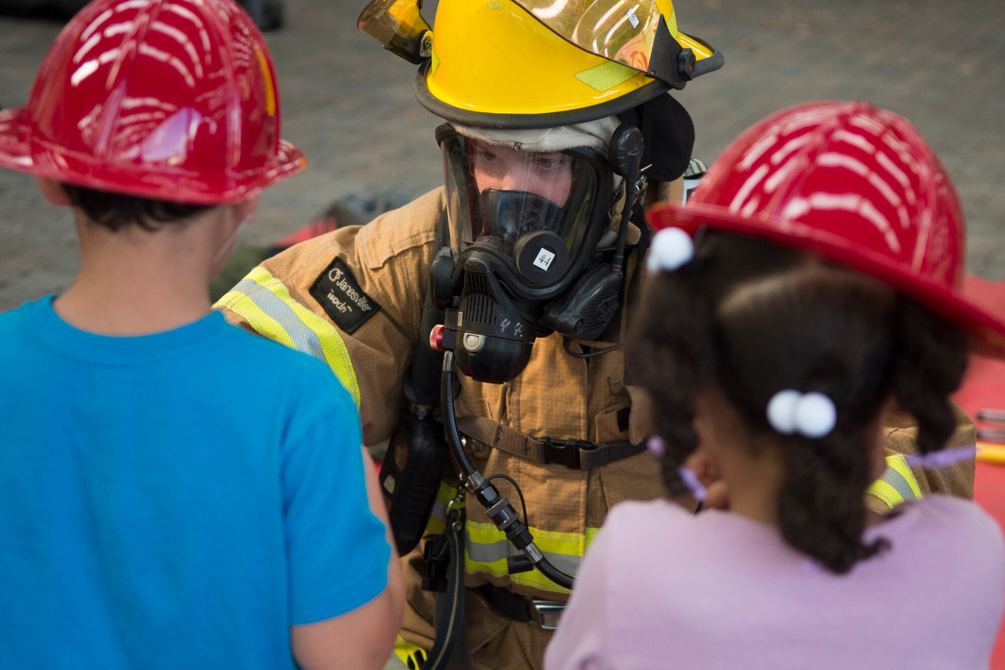 U.S. Air Force Airman 1st Class Ty Hults, a 52nd Civil Engineer Squadron firefighter, shows Bitburg Elementary School students firefighter equipment while visiting BES on Bitburg Annex, Germany, Oct. 8, 2015. The additional gear a firefighter wears weighs approximately 75 pounds. The firefighters demonstrated the importance of fire-safety to the students in observance of Fire Prevention Week. (U.S. Air Force photo by Airman 1st Class Luke J. Kitterman/Released)