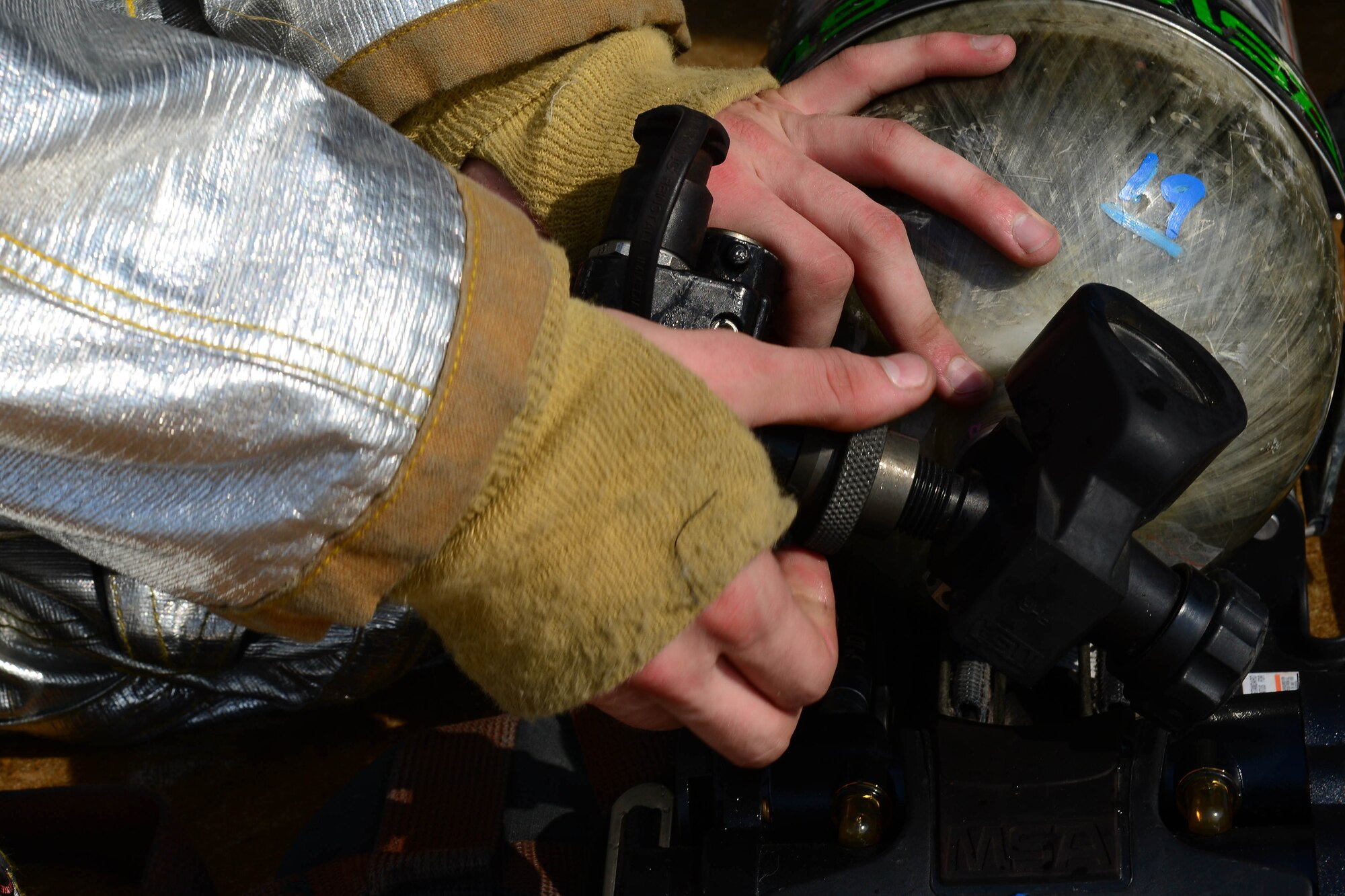 U.S. Air Force Senior Airman Joseph Cappel, 8th Civil Engineer Squadron driver operator loosens a valve from his oxygen tank to disassemble his equipment after an aircraft fire exercise during Beverly Pack 16-1 at Kunsan Air Base, Republic of Korea, Oct. 07, 2015. Along with the task of fighting fires the result ends with smoke which requires the oxygen tanks and mask to be taken care of for effective usage.  (U.S. Air Force photo by Senior Airman Ashley L. Gardner/Released)