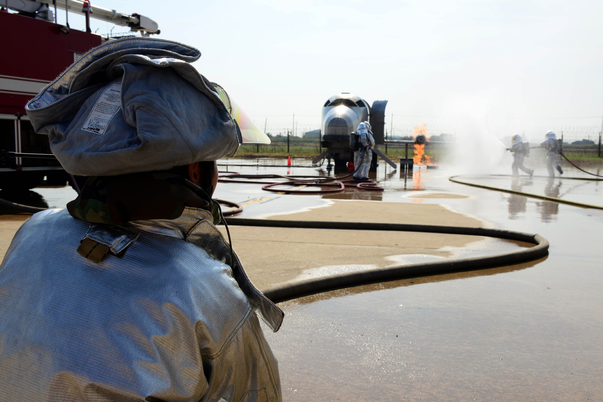 Son U Yi, 8th Civil Engineer Squadron driver operator distances himself away from the fire while helping control the water being provided to extinguish an aircraft fire exercise during Beverly Pack 16-1 at Kunsan Air Base, Republic of Korea, Oct. 07, 2015. The aircraft fire is one of the many exercises that the firefighters participate in as a refresher training to sharpen their skills in the case of a real world emergency. (U.S. Air Force photo by Senior Airman Ashley L. Gardner/Released)