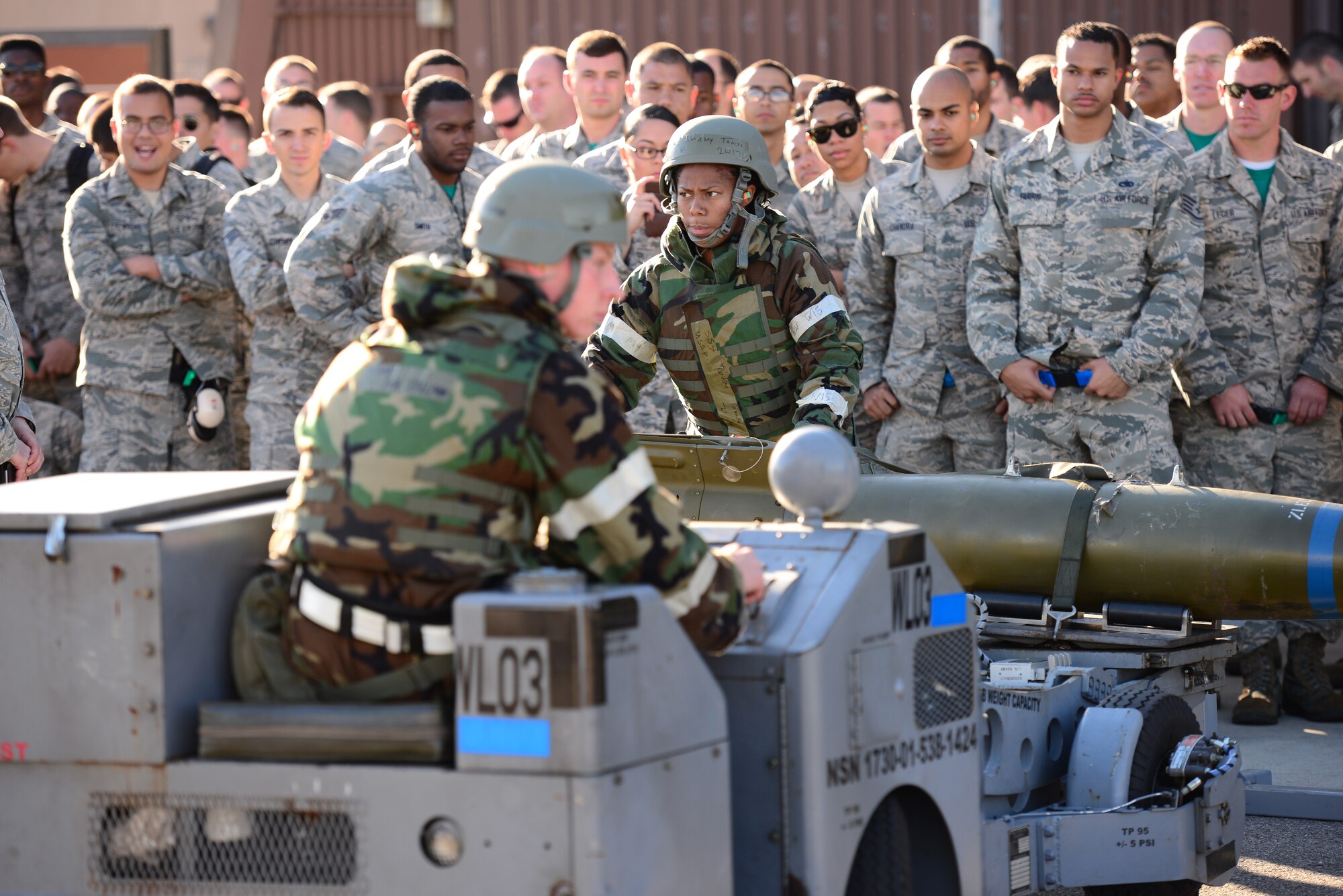 Staff Sgt. Tameka Lindsay, 25th Aircraft Maintenance Unit weapons loader, directs a practice munitions before a crowd of her peers during the quarterly load competition held at Osan Air Base, Republic of Korea, Oct. 9, 2015. This quarter the competitors completed the reload portion with the added difficulty of being in mission-oriented protective posture gear and a simulated gas attack where they had to don full MOPP 4 before continuing.
(U.S. Air Force photo/Staff Sgt. Amber Grimm)