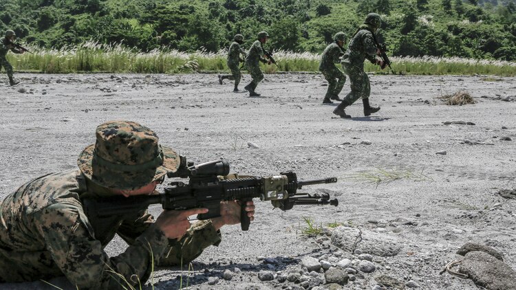 A U.S. Marine sights in on his rifle as Philippine Marines move up during squad attack training at Crow Valley, Philippines, Oct. 4, 2015. Philippine Marines and U.S. Marines with Battalion Landing Team 2nd Battalion, 5th Marine Regiment, 31st Marine Expeditionary Unit, are training side by side for Amphibious Landing Exercise 2015, an annual bilateral training exercise conducted by members of the Armed Forces of the Philippines alongside U.S. Marine and Navy Forces. 