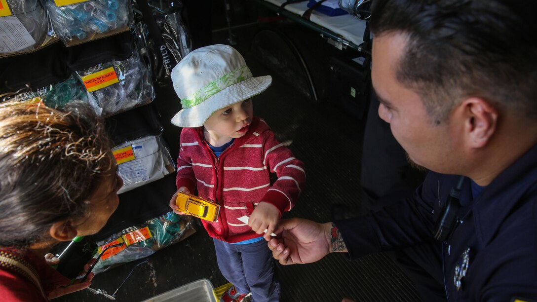 A member of the San Francisco Fire Department gives a sticker to a young young boy during a humanitarian assistance and disaster relief static display at Marina Green Park, San Francisco, Oct. 9, 2015, as part of San Francisco Fleet Week 2015. SFFW 15’ is a week-long event that blends a unique training and education program, bringing together key civilian emergency responders and Naval crisis-response forces to exchange best practices focused on humanitarian assistance disaster relief with particular emphasis on defense support to civil authorities.