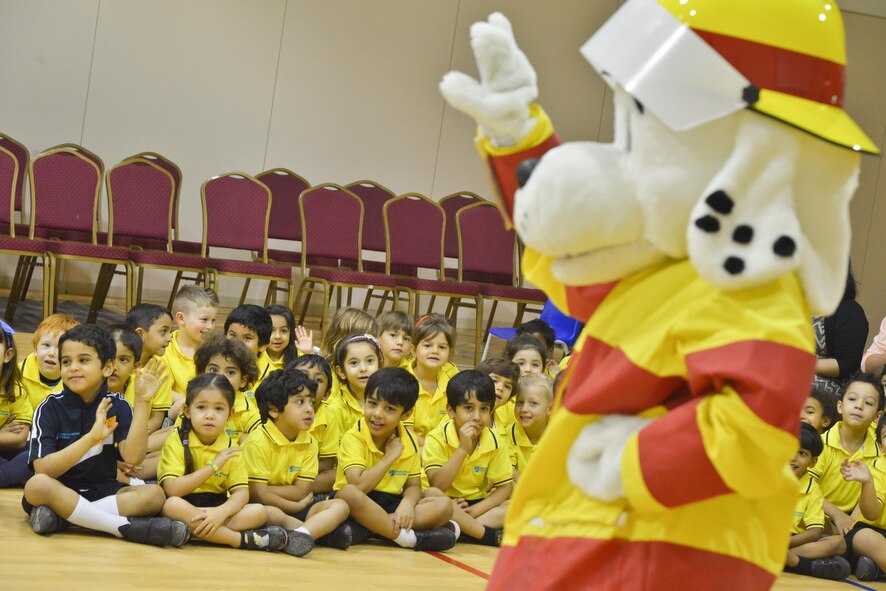 Sparky greets children as he enters their gymnasium to start their fire prevention and safety drills as part of the 379th Expeditionary Civil Engineer Squadron Fire Department Fire Prevention Week visit October 8, 2015 in Doha, Qatar. Sparky is the National Fire Protection Association mascot and has promoted fire safety to children for more than 60 years. This year's Fire Prevention Week began with a proclamation signed by 379th Air Expeditionary Wing leadership and spanned Oct. 4 through the 11th. (U.S. Air Force photo/Staff Sgt. Alexandre Montes)