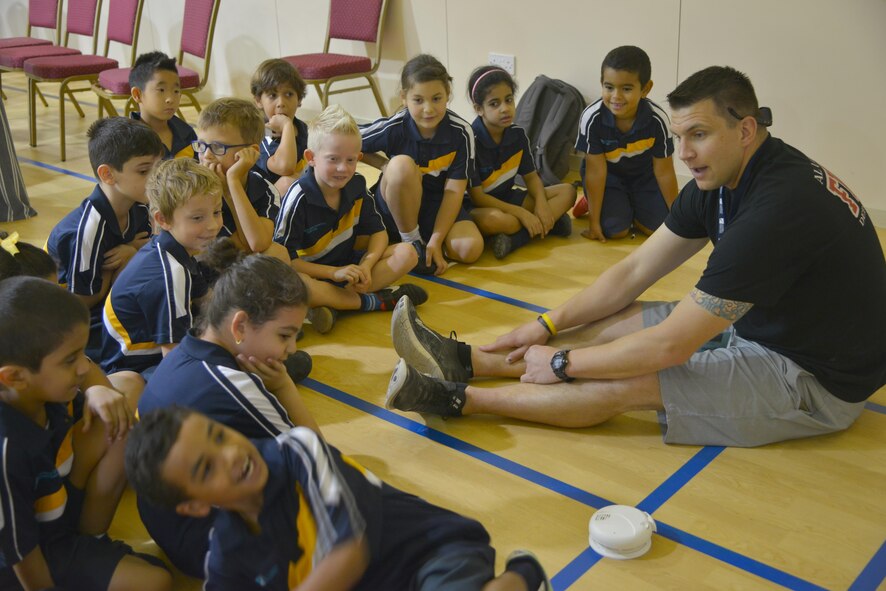 Technical Sgt. Brian Burmeister, 379th Expeditionary Civil Engineer Squadron firefighter, talks to children from Compass International School Doha about home fire alarm safety during Fire Prevention Week educational seminars October 8, 2015 in Doha, Qatar. During the visit, children were able to apply the skills taught and ask questions to further their learning.  (U.S. Air Force photo/Staff Sgt. Alexandre Montes)
