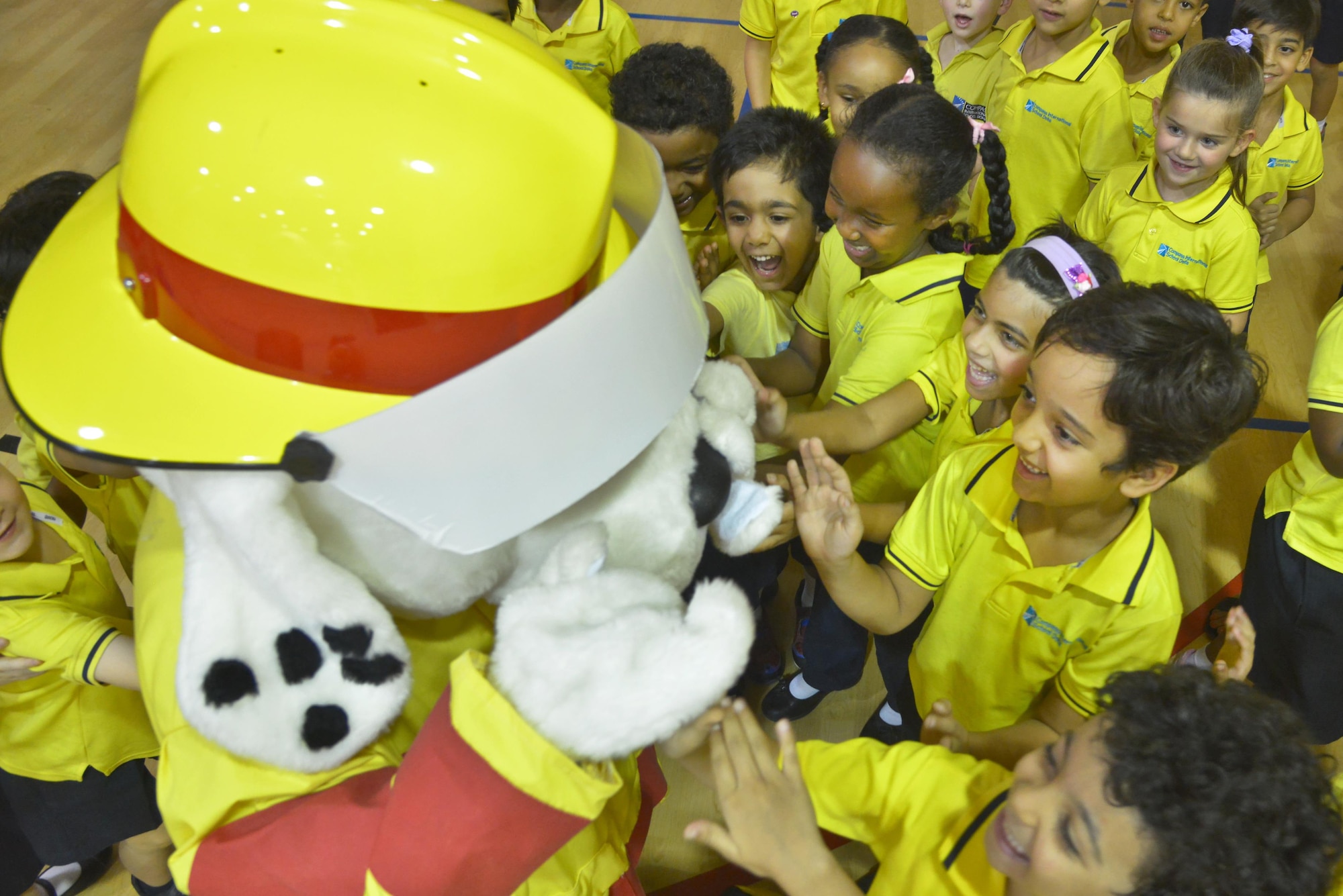 Students of the Compass International School Doha pet Sparky, National Fire Protection Association mascot during a visit as part of Fire Prevention Week educational seminars from airmen of the 379th Expeditionary Civil Engineer Squadron Fire Department October 8, 2015 in Doha, Qatar. During the visit, children were able to apply the skills taught and ask questions to further their learning. (U.S. Air Force photo/Staff Sgt. Alexandre Montes)