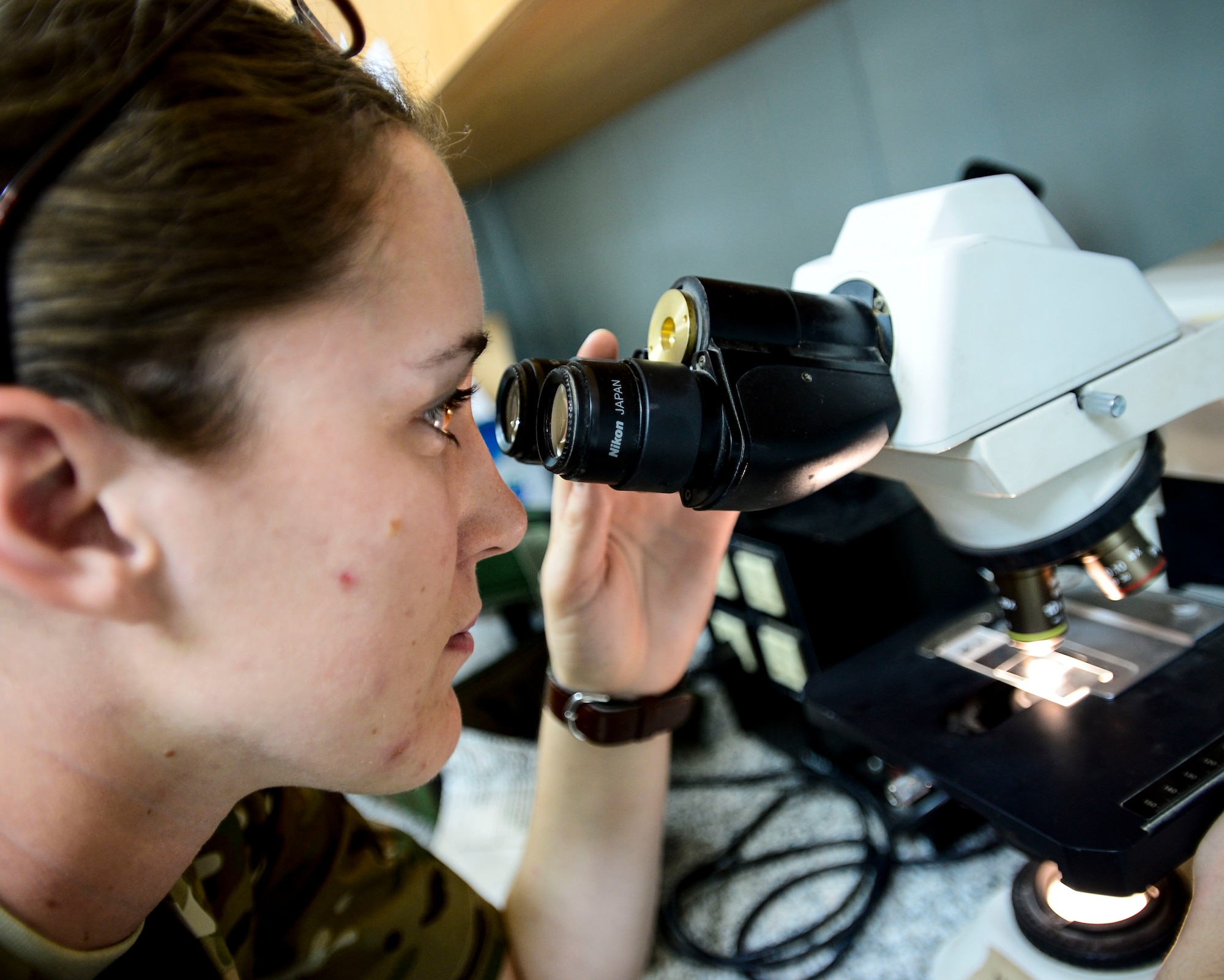 U.S. Army Private 1st Class Chelsey Therault, 463rd Military Detachment Veterinary Service veterinary technician, looks through a microscope at an undisclosed location in Southwest Asia, Sept. 28, 2015. Trap, Neuter, Vaccinate and Return is a method of humanely trapping feral cats, having them spayed or neutered, vaccinated for rabies and then returning them to their colony to live out their lives. (U.S. Air Force photo by Senior Airman Racheal E. Watson/Released)