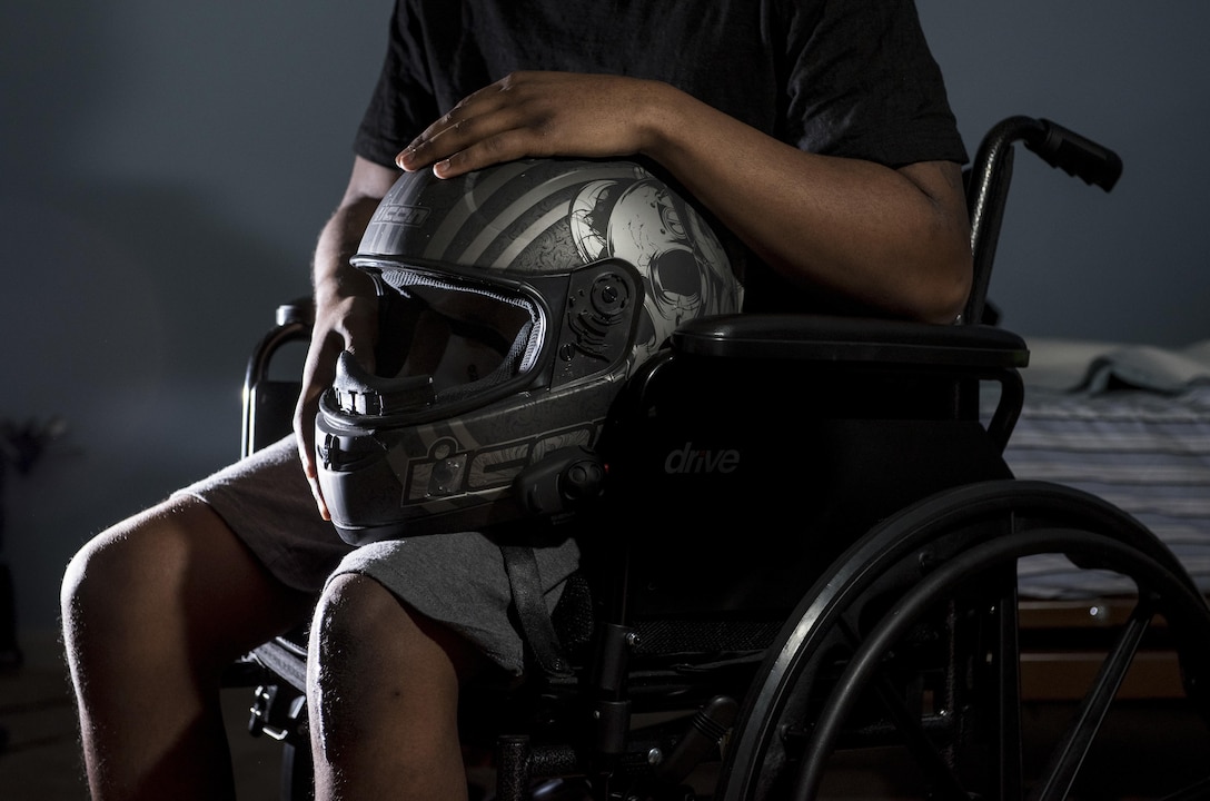 Spc. Nicolas Laboy, U.S. Army Reserve information technology specialist for the 416th Theater Engineer Command, poses in his wheelchair at his house in Bolingbrook, Ill., Sept. 29, holding his motorcycle helmet that saved his life during an accident three months earlier. Laboy is expected to walk again after three more months of physical therapy. During his accident, Laboy broke his right leg, received a third-degree burn in his left thigh, severed his kidney and liver, fractured his lower spine and his right shoulder, and suffered internal bleeding in his brain. (U.S. Army photo by Master Sgt. Michel Sauret)