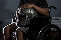 Spc. Nicolas Laboy, U.S. Army Reserve information technology specialist for the 416th Theater Engineer Command, poses in his wheelchair at his house in Bolingbrook, Ill., Sept. 29, holding his motorcycle helmet that saved his life during an accident three months earlier. Laboy is expected to walk again after three more months of physical therapy. During his accident, Laboy broke his right leg, received a third-degree burn in his left thigh, severed his kidney and liver, fractured his lower spine and his right shoulder, and suffered internal bleeding in his brain. (U.S. Army photo by Master Sgt. Michel Sauret)