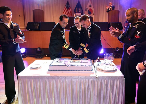 Vice Adm. Um, Hyun-Seong, commander, Republic of Korea Fleet, Rear Adm. Bill Byrne, commander of U.S. Naval Forces, Korea, and Information Systems Technician 3rd Class Jessica Reinaccius cut a ceremonial cake during the 240th Navy Birthday celebration in Busan. (U.S. Navy photo by Mass Communication Specialist 1st Class Abraham Essenmacher/Released)