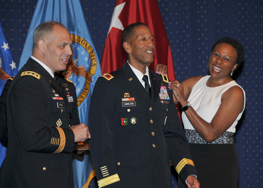 Army Brig. Gen. Charles R. Hamilton, center, gets promoted by Army Deputy Chief of Staff for Logistics Lt. Gen. Gustave F. Perna, and Hamilton’s wife Regina during a promotion ceremony July 10 at Fort Belvoir, Virginia. Hamilton was promoted days before he took command of DLA Troop Support at a change of command ceremony July 13.