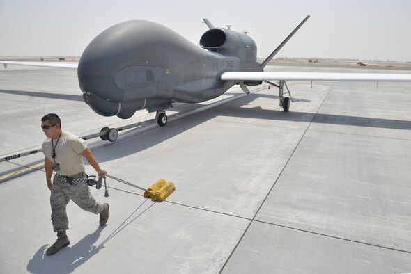 An Airman pulls a set of chalks while escorting a RQ-4 Global Hawk back to a hangar during ground operations at an undisclosed location in Southwest Asia Sept. 18, 2015. The Global Hawk block 20 aircraft carry the Battlefield Airborne Communication Node payload, which ensures connectivity for warfighters. The BACN system, managed out of Hanscom Air Force Base, Mass., recently achieved 100,000 combat flight hours. (U.S. Air Force photo/Tech. Sgt. Christopher Boitz)