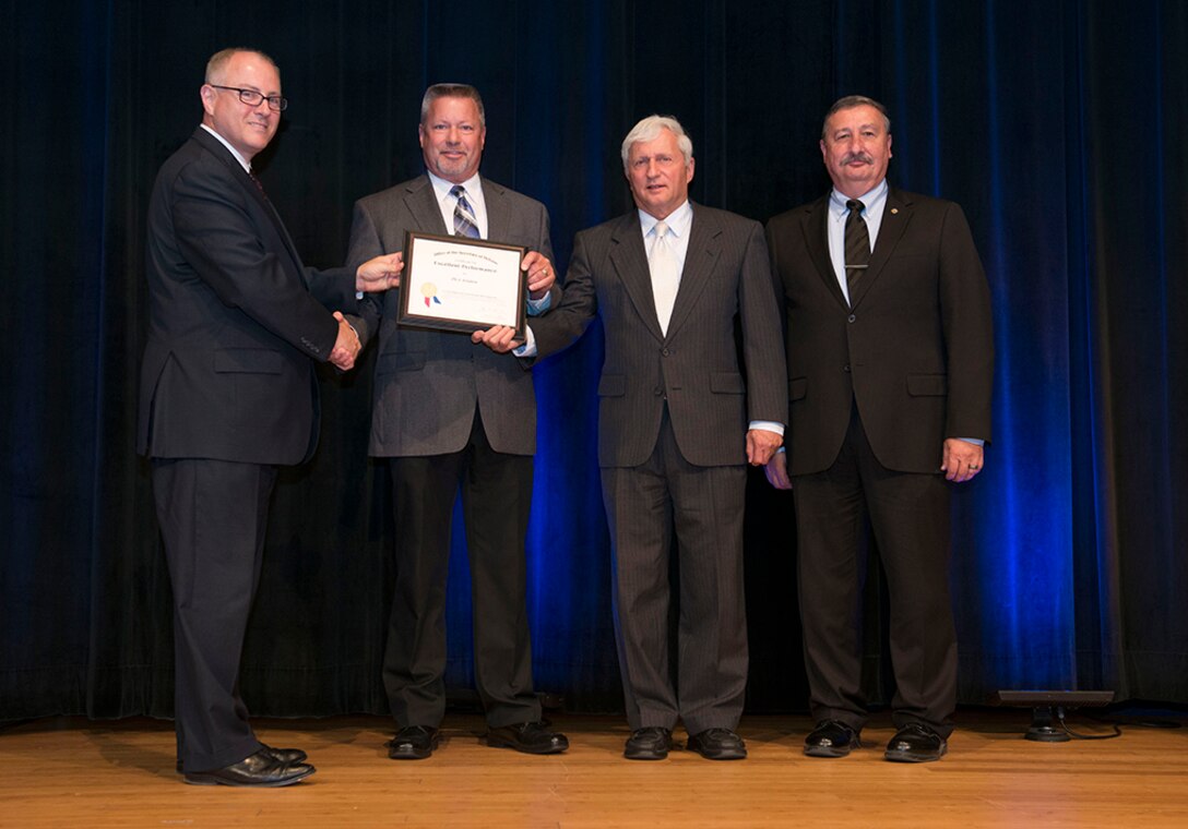 Stephen Welby, deputy assistant secretary of defense for systems engineering, left, poses with the DoD Value Engineering Achievement Award winners from DLA Aviation: Dave Carns and Tom Kennedy, along with Ted Case, DLA vice director. The Department of Defense presented the FY 2014 Department of Defense Value Engineering Achievement Awards during a ceremony at the Pentagon, Washington, D.C., June 25, 2015. 