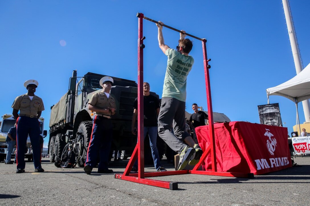 US Marine Corps recruiters from the San Francisco area  watch a visitor conduct the pull-up challenge during a static ship display on Pier 80 as part of San Francisco Fleet Week 2015, Oct. 10. SFFW 15’ is a week-long event that blends a unique training and education program, bringing together key civilian emergency responders and Naval crisis-response forces to exchange best practices focused on humanitarian assistance disaster relief with particular emphasis on defense support to civil authorities.