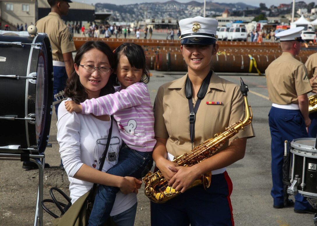 Corporal Jessica Larson, a saxophone player with the 1st Marine Division Band, poses for a photo with San Francisco residents during a ship display on Pier 80 as part of San Francisco Fleet Week 2015, Oct. 10. SFFW 15’ is a week-long event that blends a unique training and education program, bringing together key civilian emergency responders and Naval crisis-response forces to exchange best practices focused on humanitarian assistance disaster relief with particular emphasis on defense support to civil authorities.