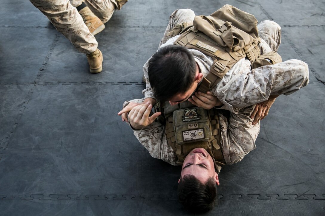 ARABIAN GULF (Oct. 10, 2015) U.S. Marines Cpl. Jeremiah Patterson, bottom, and Lance Cpl. Antonio Renteria grapple during a deck shoot aboard the amphibious assault ship USS Essex (LHD 2). These Marines are riflemen with Lima Company, Battalion Landing Team 3rd Battalion, 1st Marine Regiment, 15th Marine Expeditionary Unit. The Marines ran and grappled between their shooting to raise their heart rate and practice shooting while their bodies were fatigued. The 15th MEU, embarked aboard the ships of the Essex ARG, is deployed to maintain regional security in the U.S. 5th Fleet area of operations. (U.S. Marine Corps photo by Cpl. Anna Albrecht/Released)