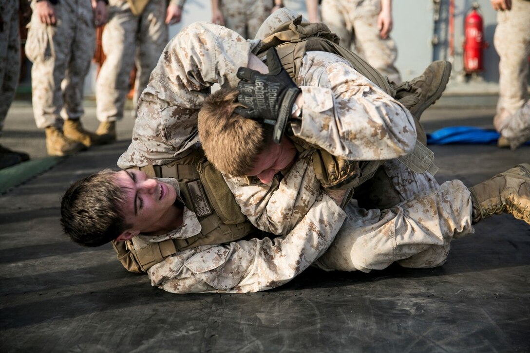 ARABIAN GULF (Oct. 10, 2015) U.S. Marines with Lima Company, Battalion Landing Team 3rd Battalion, 1st Marine Regiment, 15th Marine Expeditionary Unit, grapple during a deck shoot aboard the amphibious assault ship USS Essex (LHD 2). The Marines ran and grappled between their shooting to raise their heart rate and practice shooting while their bodies were fatigued. The 15th MEU, embarked aboard the ships of the Essex ARG, is deployed to maintain regional security in the U.S. 5th Fleet area of operations. (U.S. Marine Corps photo by Cpl. Anna Albrecht/Released)
