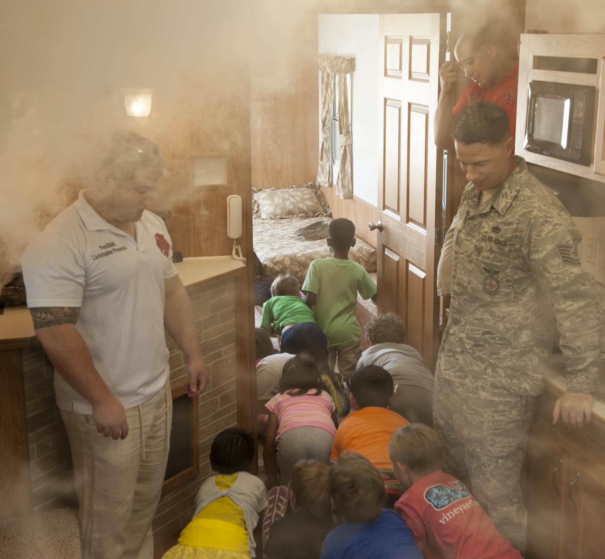 U.S. Air Force firefighters from the 18th Civil Engineer Squadron, Tech. Sgt. Christopher Provencal and Tech. Sgt. Joseph Price, instruct Kadena Elementary School children on what to do in the event of a fire Oct. 7, 2015, on Kadena Air Base, Japan. A demonstration was held to inform children about the importance of testing smoke alarms as part of Fire Prevention Week. This year’s theme is “hear the beep where you sleep”. (U.S. Air Force photo by Airman 1st Class Corey M. Pettis/Released)