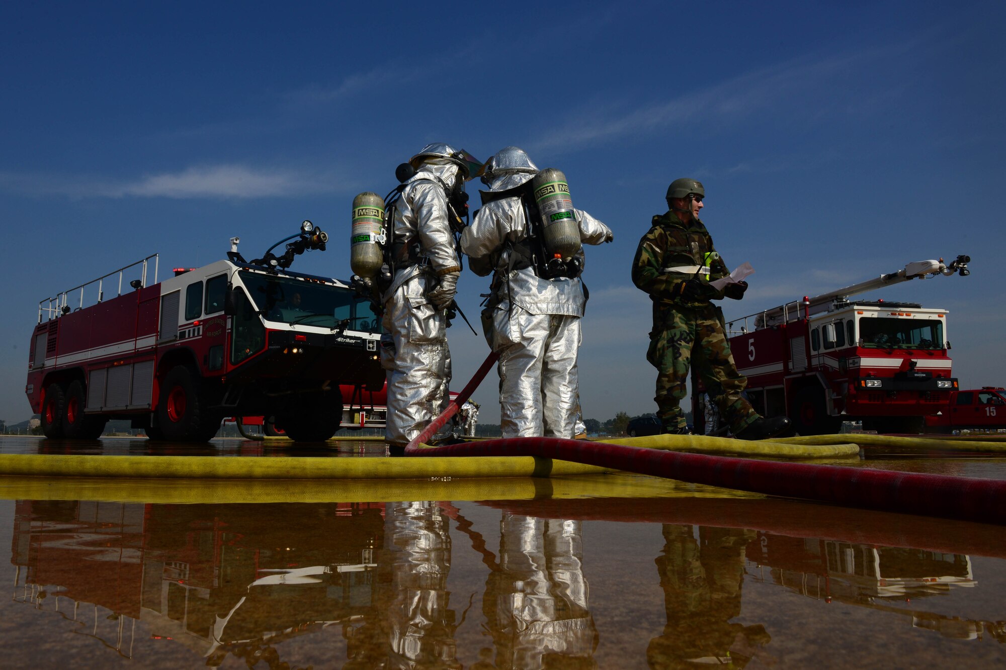 Firefighters from the 8th Civil Engineer Squadron communicate with each other while participating in an aircraft fire exercise during Beverly Pack 16-1 at Kunsan Air Base, Republic of Korea, Oct. 07, 2015. The aircraft fire is one of the many exercises that the firefighters participate in as a refresher training to sharpen their skills in the case of a real world emergency. (U.S. Air Force photo by Senior Airman Ashley L. Gardner/Released)
