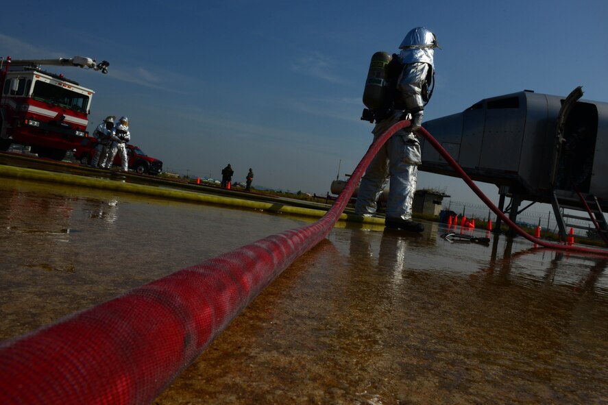 An 8th Civil Engineer Squadron Airman holds the water hose while fellow firefighters extinguish an aircraft fire during Beverly Pack 16-1 at Kunsan Air Base, Republic of Korea, Oct. 07, 2015. The aircraft fire is one of the many exercises that the firefighters participate in as a refresher training to sharpen their skills in the case of a real world emergency. (U.S. Air Force photo by Senior Airman Ashley L. Gardner/Released)
