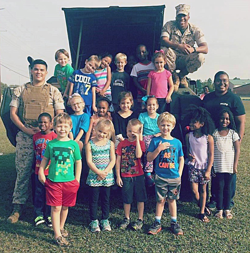 Sgt. Thomas Over, platoon sergeant, and Cpl. Devante Mimms, licensing noncommissioned  officer, both with Logistics Support Division, Marine Corps Logistics Base Albany, volunteer to support the annual Transportation Day event at Worth County Primary School in Sylvester, Ga., Oct. 9. They drove a high mobility multi-wheeled vehicle to the school for the students to see, touch and learn about.