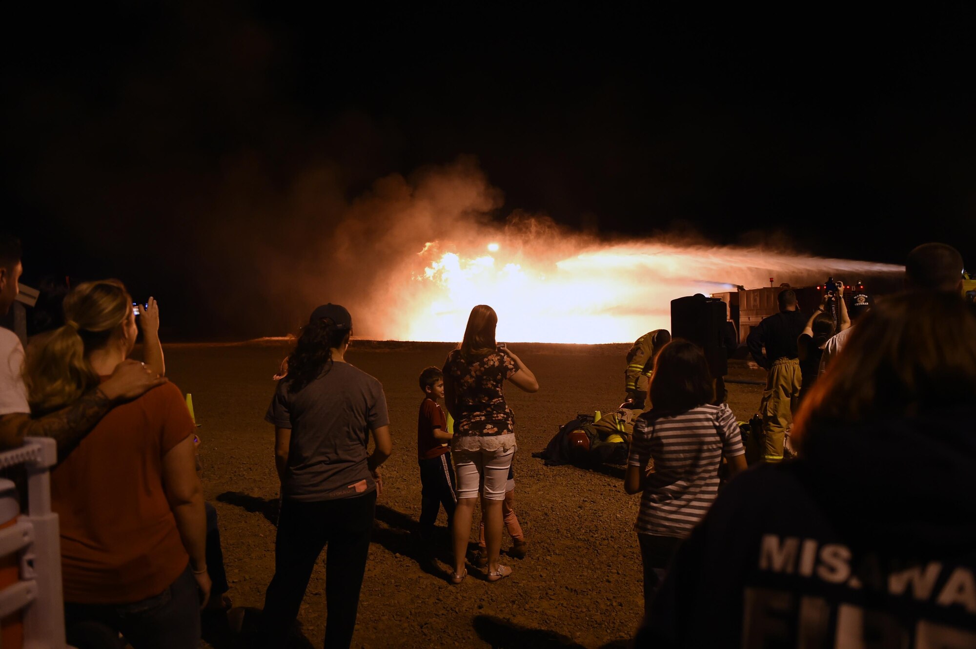 ALTUS AIR FORCE BASE, Okla. – Airmen and their families watch as members of the 97th Civil Engineer Squadron Fire Department extinguish a fire during a firefighting demonstration, Oct. 7 at the live-fire training area. Spectators were able to see how the fire department uses their tools and equipment to contain and extinguish fires. (U.S. Air Force photo by Senior Airman Dillon Davis/Released)