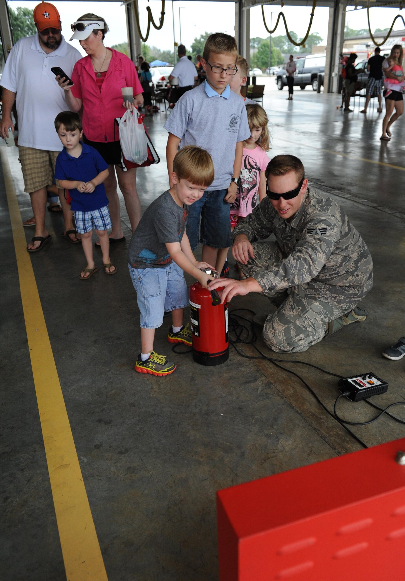 Senior Airman Seth Corn, 81st Infrastructure Division driver and operator, assists Brando Conger, son of Tech. Sgt. Rob Conger, 85th Engineering Installation Squadron airfield systems team chief, with using an electric fire extinguisher during the Keesler Fire Department open house at the fire station Oct. 10, 2015, Keesler Air Force Base, Miss. The open house was the conclusion event to Fire Prevention Week. Throughout the week the Keesler Fire Department conducted random fire drills, toured various facilities with Sparky the Fire Dog, passed out fire safety information and fire hats for children and provided stove and fire extinguisher demonstrations. (U.S. Air Force photo by Kemberly Groue)