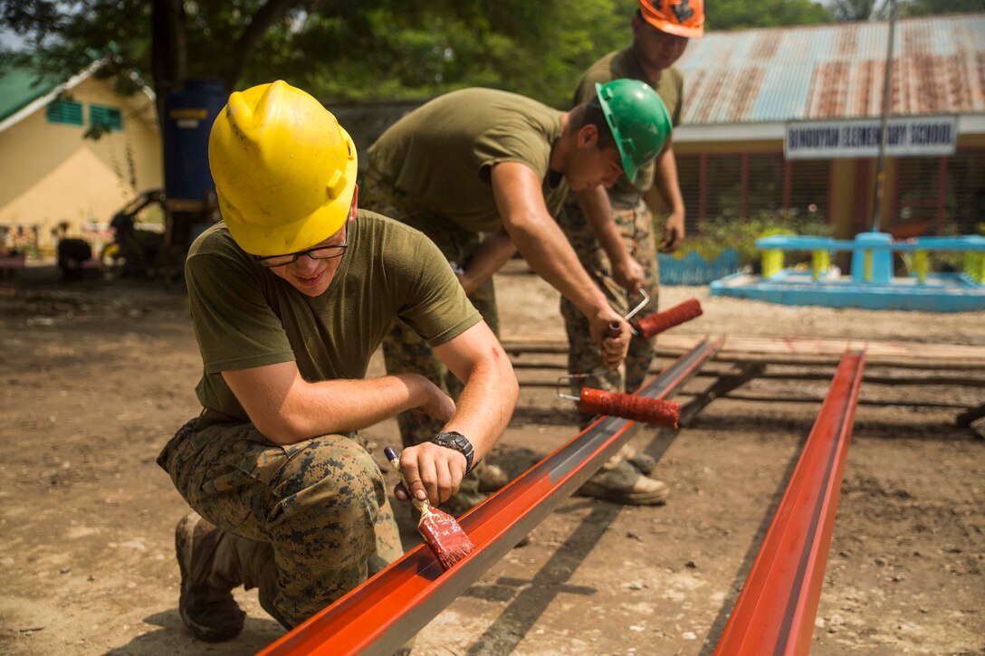 U.S. service members work together to paint metal beams while working on the humanitarian civic assistance project at Binduyan Elementary School Sept. 30, during Amphibious Landing Exercise 2015 (PHIBLEX 15). PHIBLEX 15 is an annual, bilateral training exercise conducted by members of the Armed Forces of the Philippines alongside U.S. Marine and Navy Forces. It focuses on strengthening the partnership and relationships between the two nations across a range of military operations, including disaster relief and complex expeditionary operations. the metal will be used to make an overhang for the school. The service members are with 9th Engineer Support Battalion, 3rd Marine Logistics Group, III Marine Expeditionary Force.