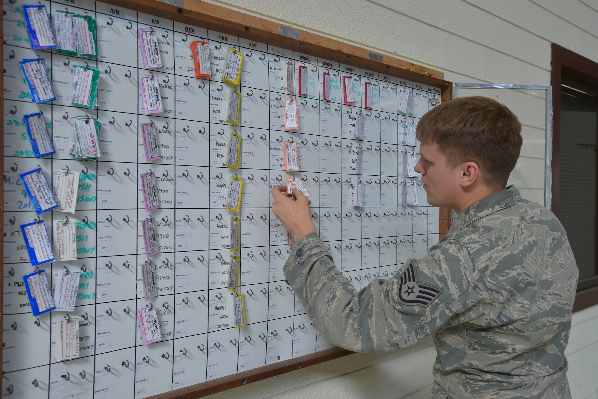 Staff Sgt. Eric Peters, 374th Maintenance Squadron instrument and flight control systems craftsman, places a warning tag on a tracking board at Yokota Air Base, Japan, Oct. 8, 2015. By having the new paperless process, the flight is able to have multiple users on different computers and tablets to spend less time waiting to look through binders. (U.S. Air Force photo by Senior Airman David Owsianka/Released)