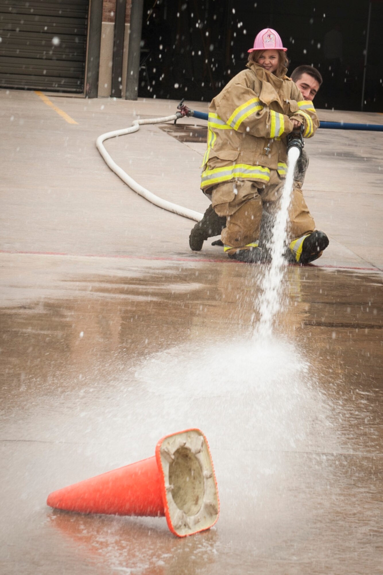 PETERSON AIR FORCE BASE, Colo. -- Grace Doyle, 7, knocks a cone over when testing out the fire hose and seeing how powerful it is Oct. 3, 2015 at the open house at the Peterson Air Force Base Fire Station. The open kicked-off National Fire Prevention Week and give Peterson Airmen and their families more knowledge about fire safety and what to do in case of emergencies. (U.S. Air Force photo by Senior Airman Rose Gudex)