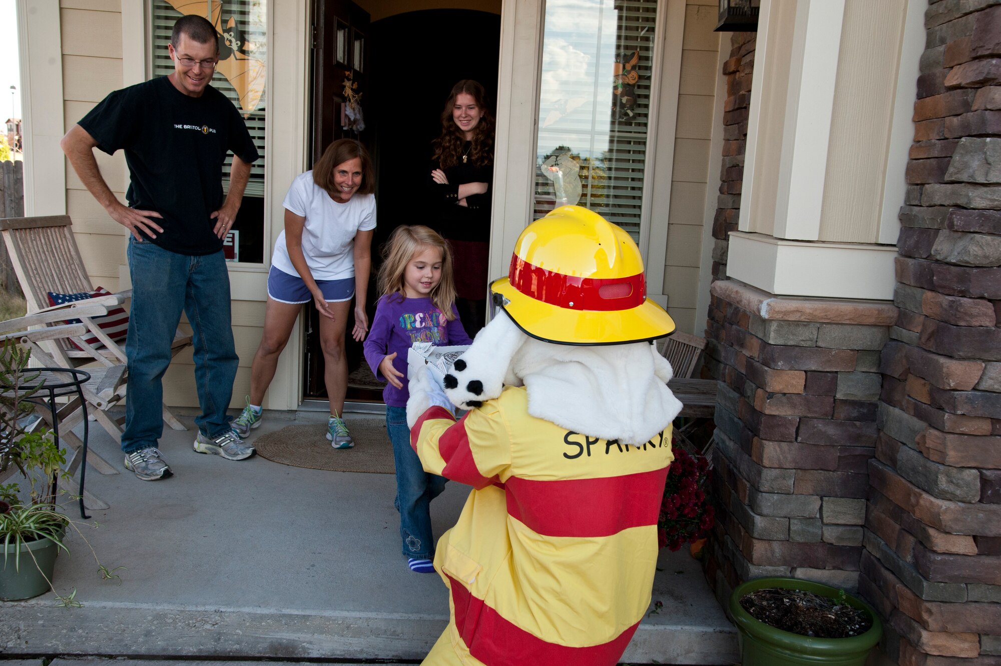 PETERSON AIR FORCE BASE, Colo. – Sparky, the fire dog, and Airmen from the 21st Civil Engineering Squadron fire station, and representatives from Terra Vista and The Club stop by Col. Susan Moran, 21st Medical Group commander, home to check their fire alarms to possibly win free pizzas during Fire Prevention Week, Oct. 5, 2015. The fire station is not only making trips to Terra Vista residents’ houses but is also visiting schools, the child development centers and a Fire Department sponsored fire muster at The Club. (U.S. Air Force photo by Senior Airman Tiffany DeNault)