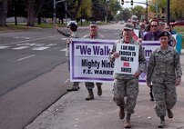 Col. Hans Ritschard, 90th Medical Group commander, leads Mighty Ninety Airmen down a main street of F.E. Warren Air Force Base, Wyo., Oct. 9, 2015, during a domestic violence walk. Men and women carried signs aimed to spread awareness of domestic violence to Airmen driving by. (U.S. Air Force photo by Senior Airman Brandon Valle)