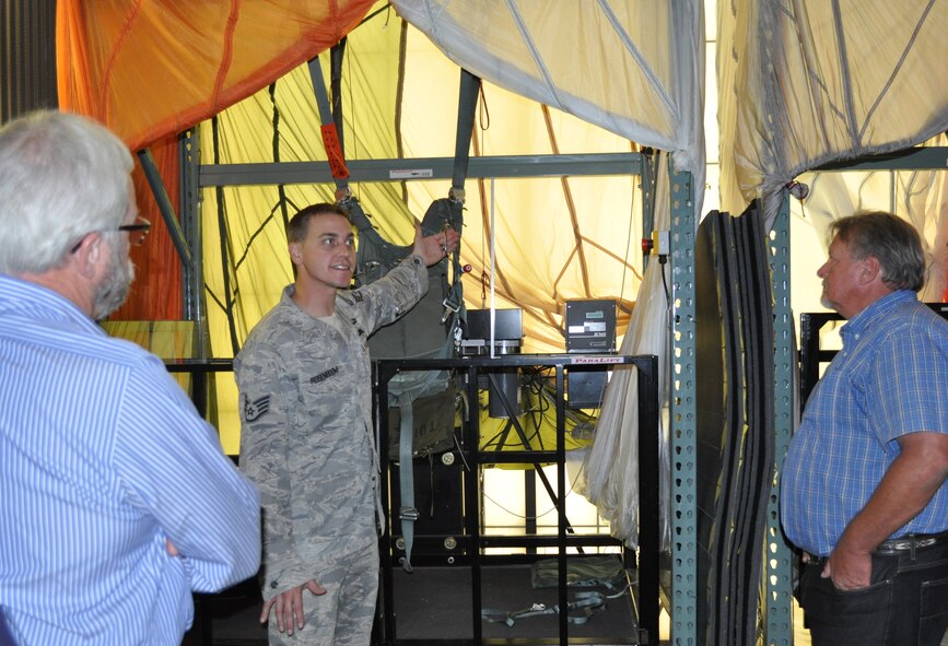 Staff Sgt. Mark Rosenboom points out features of a parachute to civic leaders  Scott Farmer, left, and  Jack Caldwell, right. Rosenboom is a Survival, Evasion, Resistance and Escape instructor for the 60th Operations Support Squadron. (U. S. Air Force photo/Ellen Hatfield)

